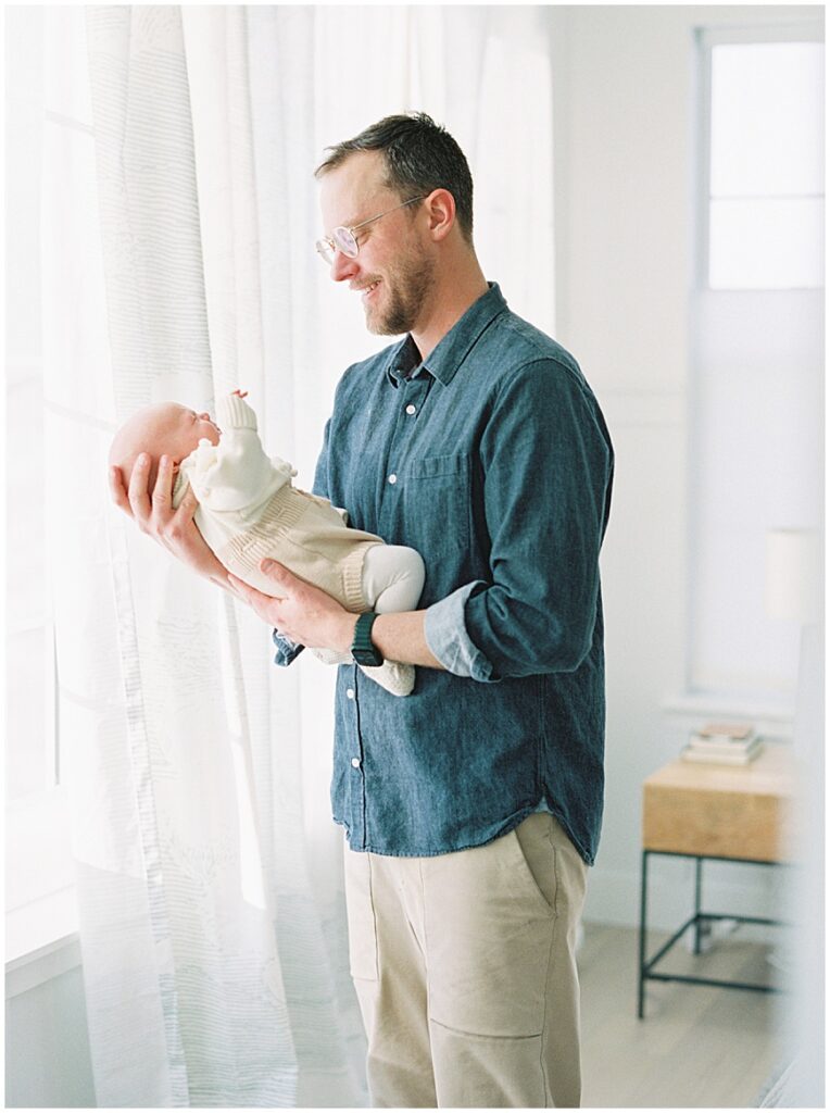 Father holding baby in bedroom during newborn session