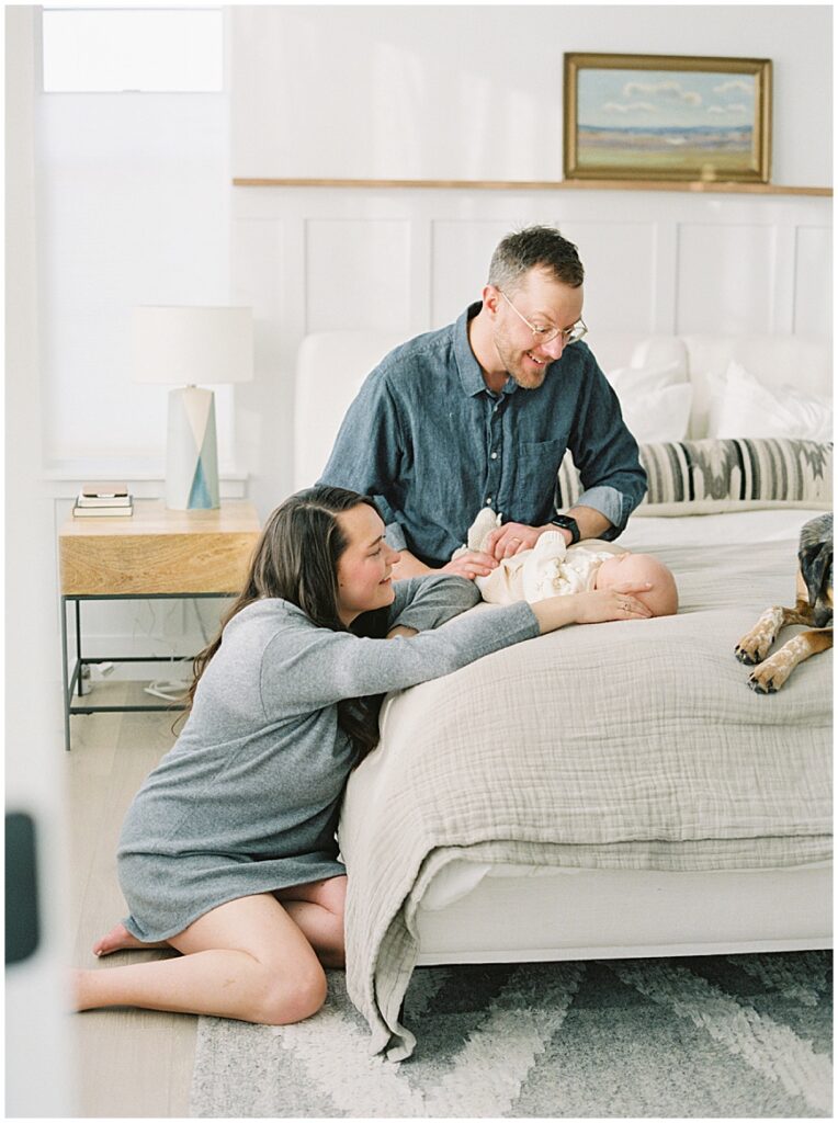 Mother & father holding baby in bedroom during newborn session