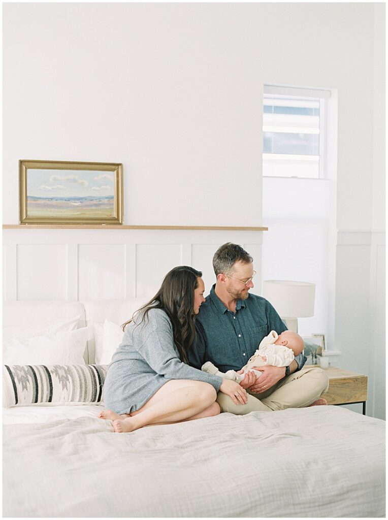 Mother & father holding baby in bedroom during newborn session