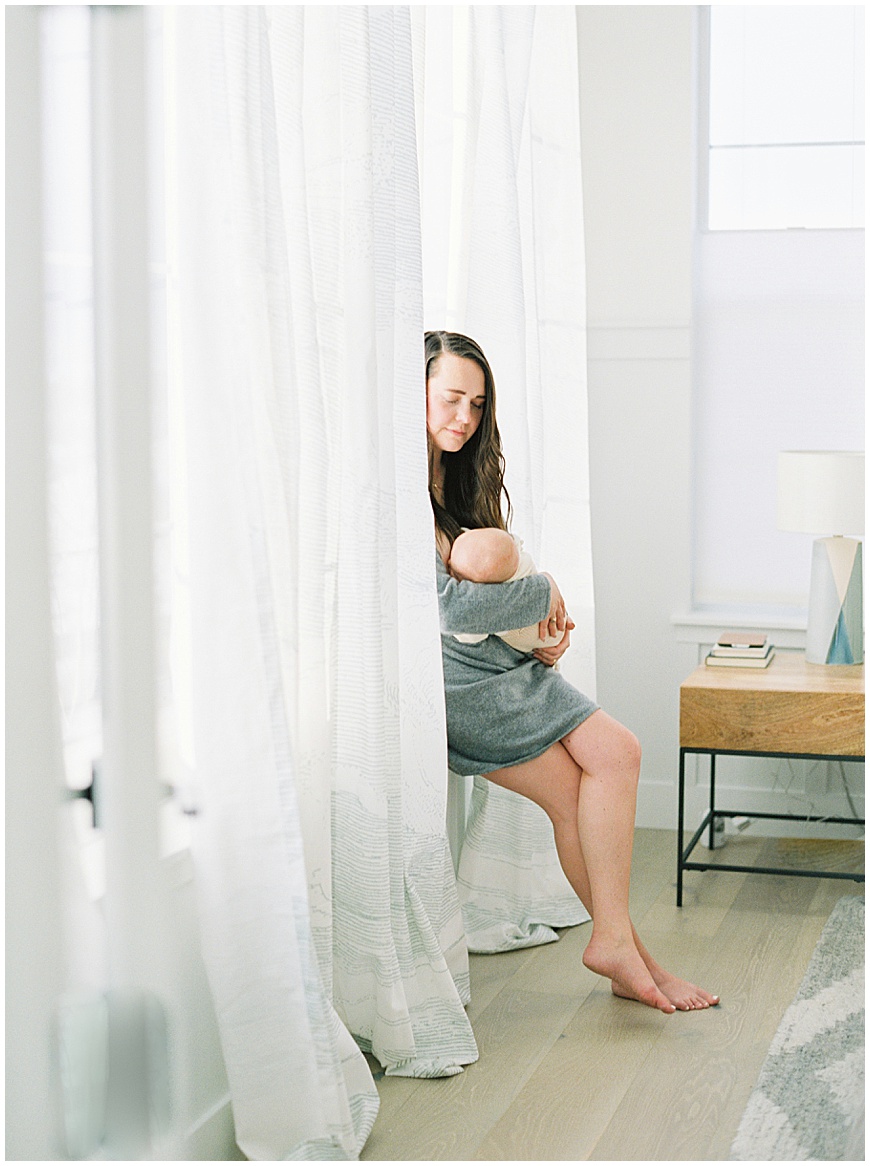 Mother holding baby in bedroom during newborn session