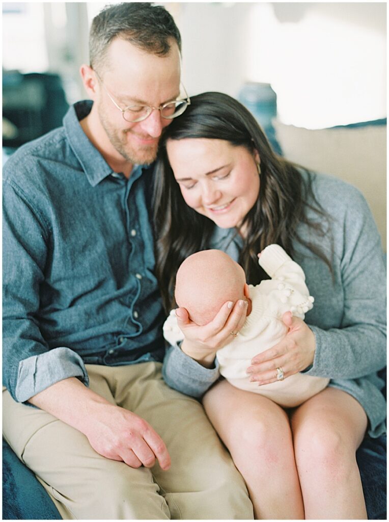 Mother & father holding baby in living room during newborn session