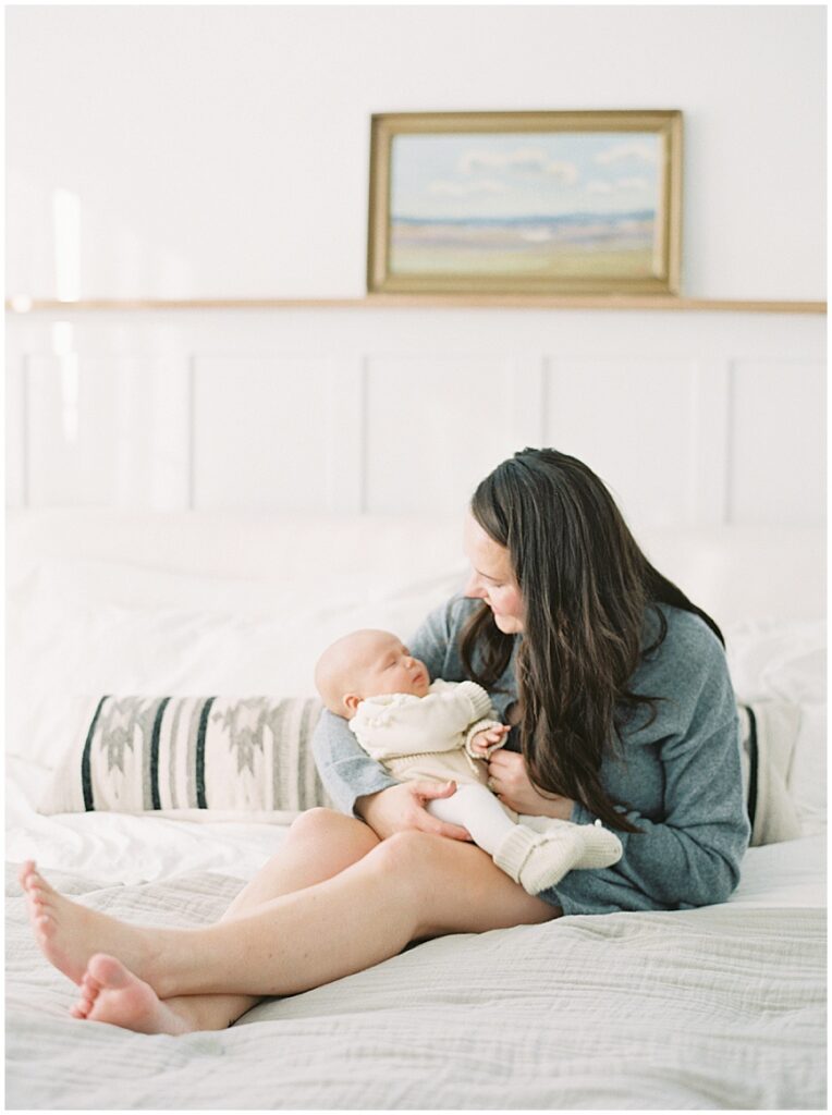 Mother holding baby in bedroom during newborn session