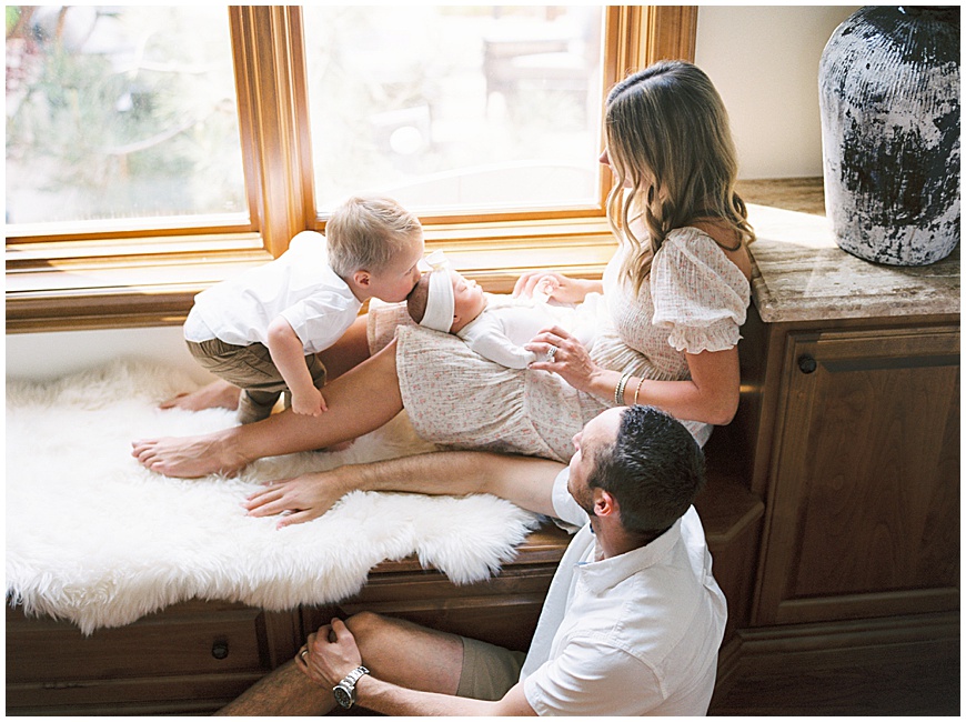 family snuggling on window bench
