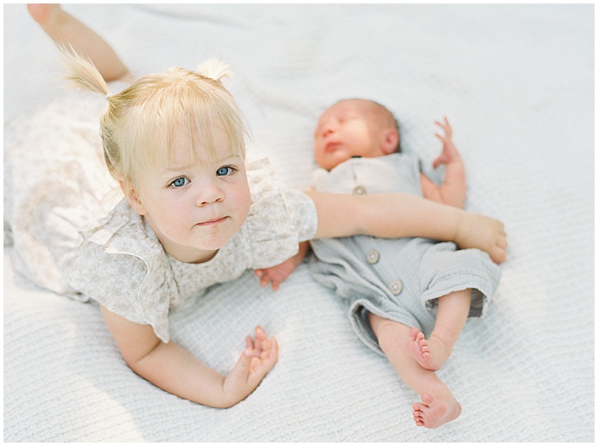 Toddler and baby on blanket during newborn session.