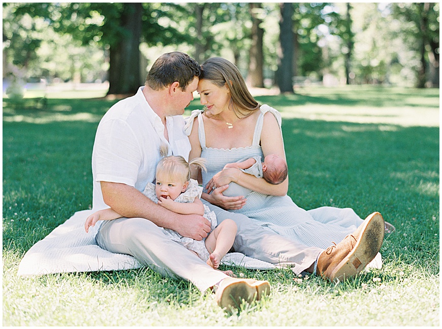 Baby, toddler, mother and father in grass during newborn session