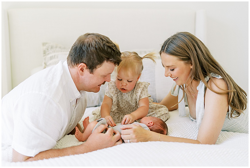 Baby, toddler, mother and father on bed during newborn session